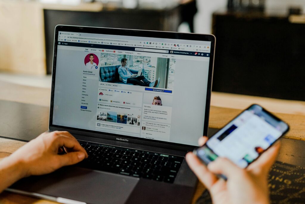 Persoon gebruikt laptop en smartphone om actief te zijn op sociale media.