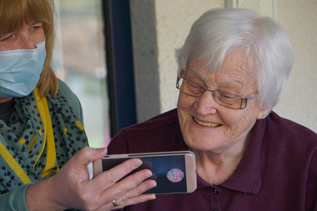 Een oudere vrouw die met plezier een smartphone gebruikt, symbool voor de digitalisering en koopkracht van senioren.