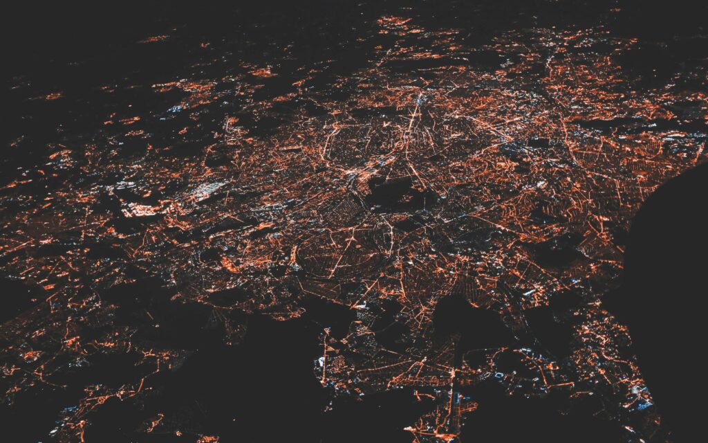 Luchtfoto van een stad bij nacht met verlichte netwerken die verbondenheid symboliseren.